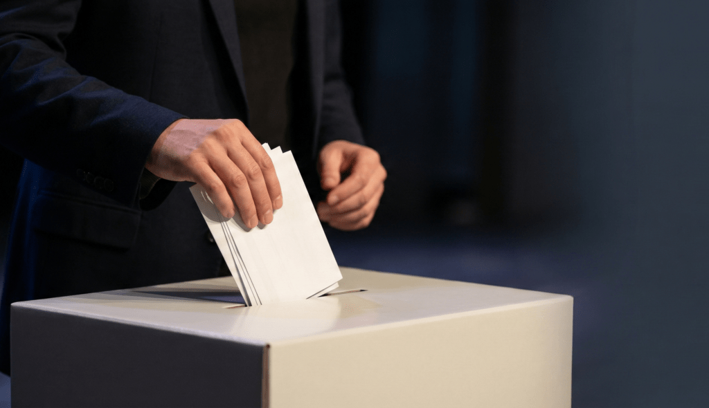 2026年九合一選舉 農漁會、水利會選舉策略:如何打贏一場「不是選舉」的選戰?戰國策網軍行銷有限公司-提供專業網軍行銷、口碑行銷 、社群行銷服務 投票人將選票投入投票箱,象徵民主選舉的重要時刻。